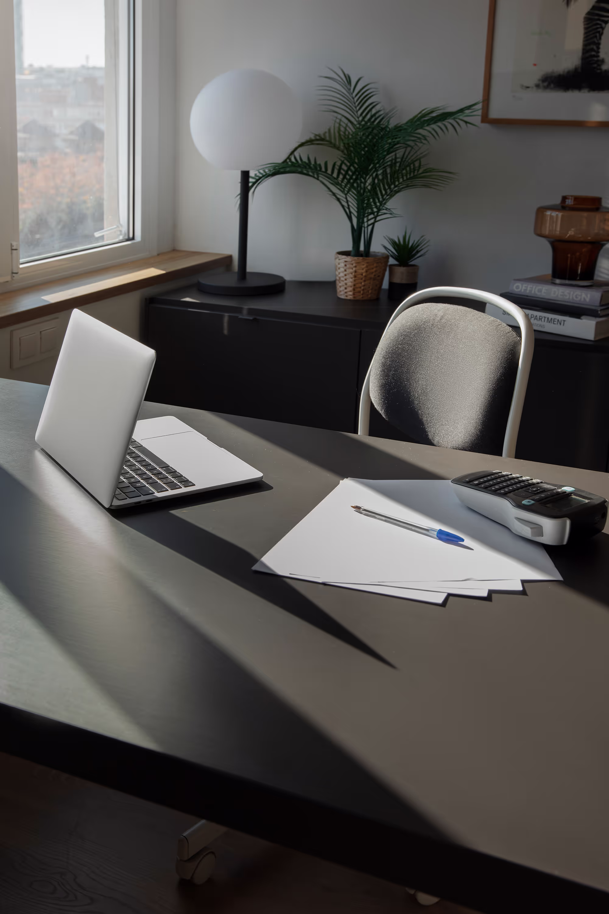 Modern desk with laptop, papers, and potted plants