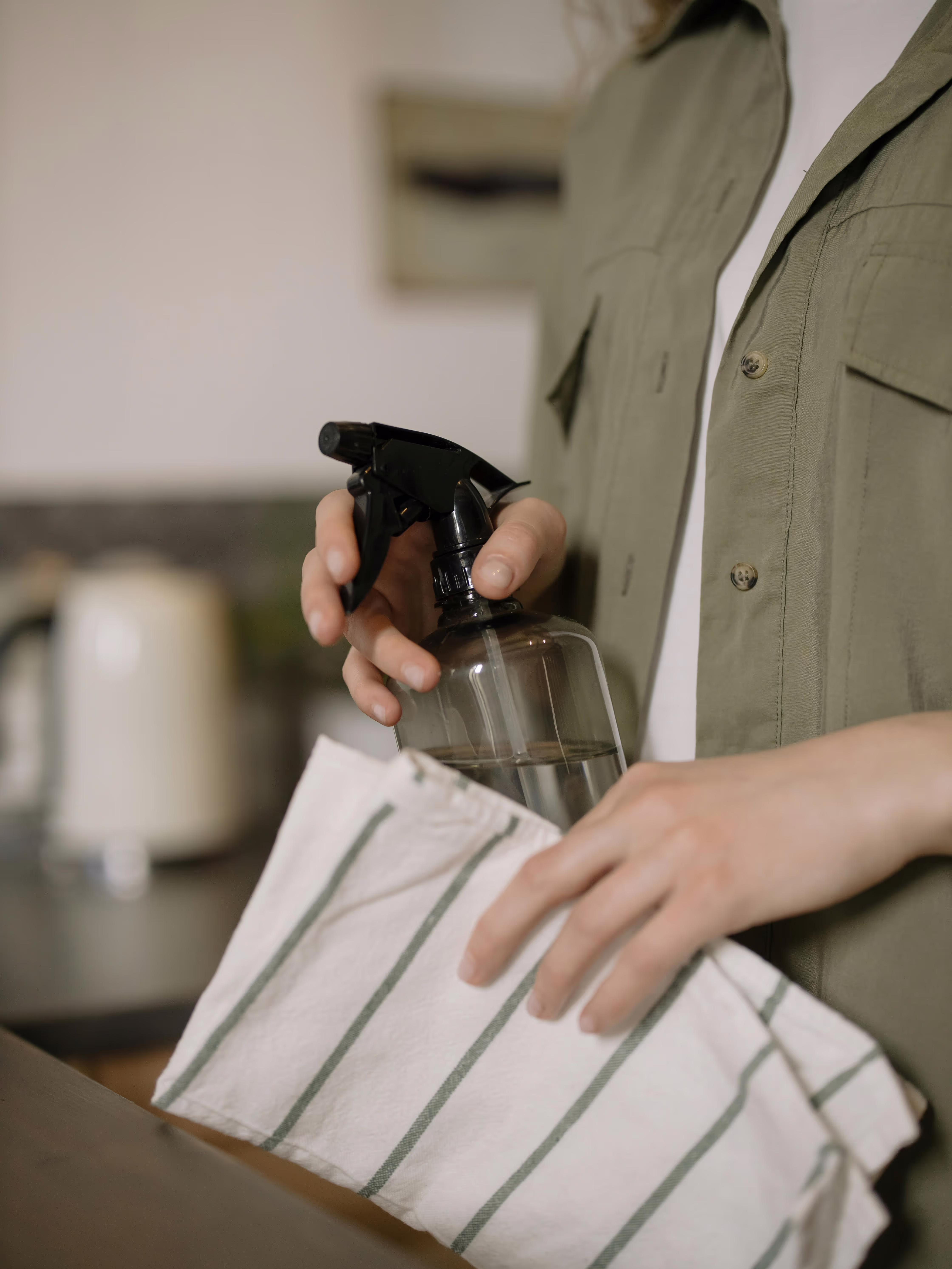 Person holding spray bottle and striped cloth for cleaning